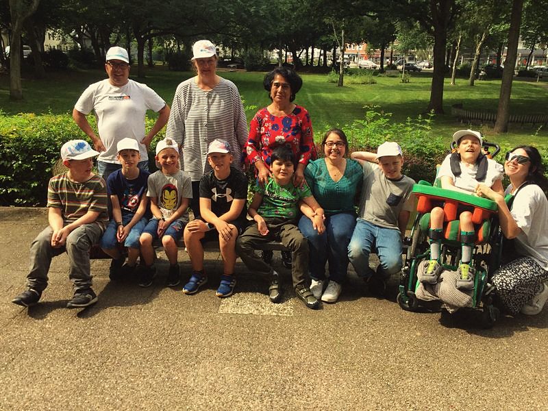 Gruppenbild mit Kindern, einem Kind im Rollstuhl und dem Betreuerteam im Park