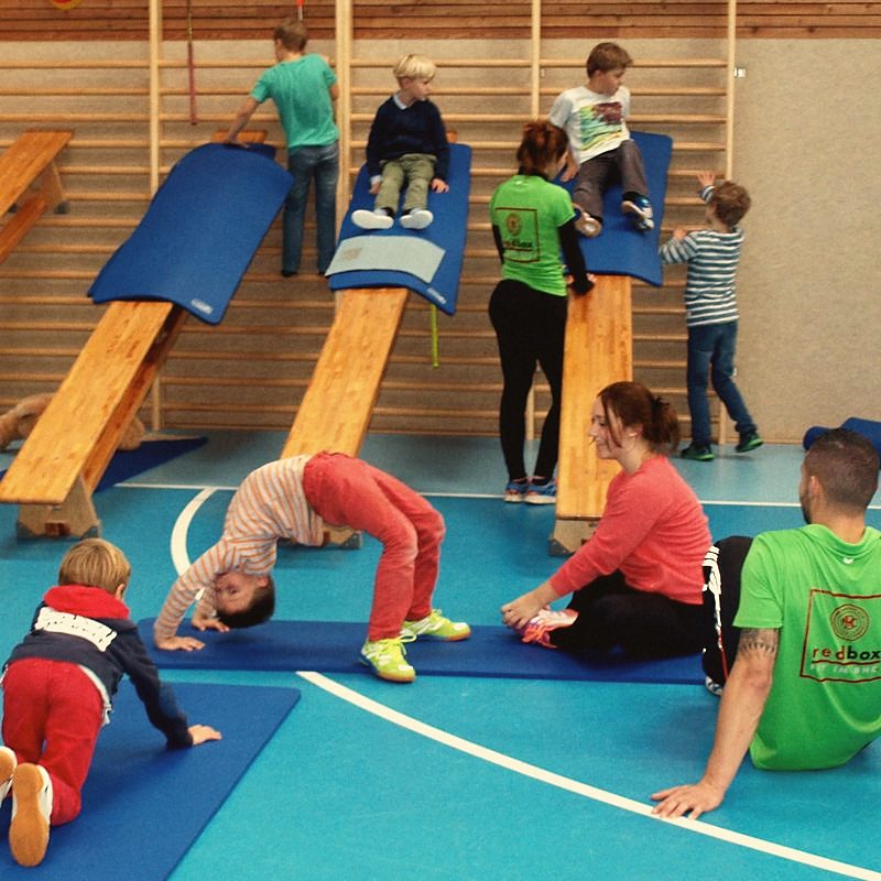 Kinder turnen auf Matten in einer Sporthalle